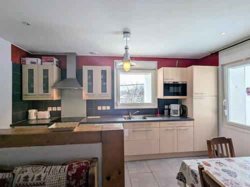 une cuisine avec des armoires blanches, un évier et une fenêtre dans l'établissement Gîte Neuf et Confortable avec Terrasse, Proche Lacs et Skis à Xonrupt-Longemer - FR-1-589-218, à Xonrupt-Longemer