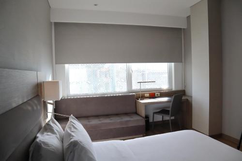 a bedroom with a bed and a desk and a window at AC Hotel by Marriott Bogota Zona T in Bogotá