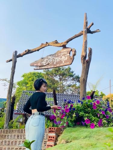 a statue of a woman standing next to flowers at Đồi Gió Hú Homestay & Coffee Măng Đen in Kon Von Kla