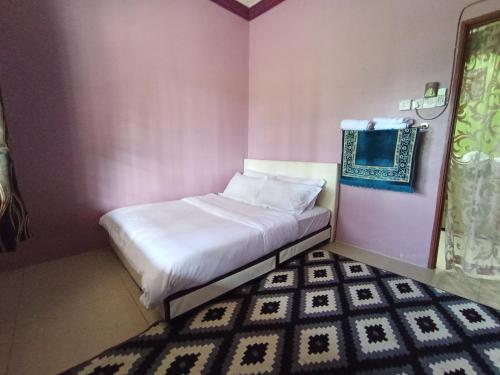 a small pink room with a bed and a rug at Homestay Tok Wan in Jertih