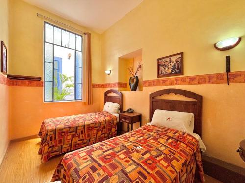 a hotel room with two beds and a window at Hotel La Alhondiga in Puebla