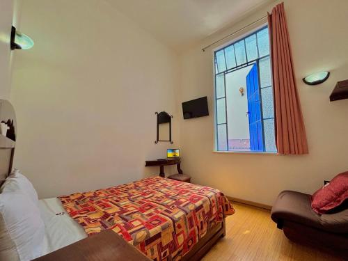 a bedroom with a bed and a window at Hotel La Alhondiga in Puebla