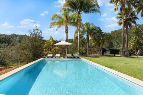 a swimming pool with two chairs and an umbrella at Villa Universe in Sant Rafael de Sa Creu