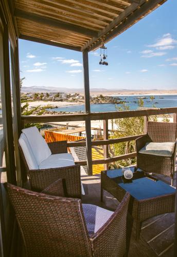 a porch with chairs and tables and a view of the ocean at Aldea Bahiguana Piso Privado 5 personas in Bahia Inglesa