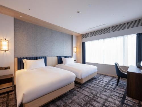 a hotel room with two beds and a desk at ANA Crowne Plaza Akita by IHG in Akita