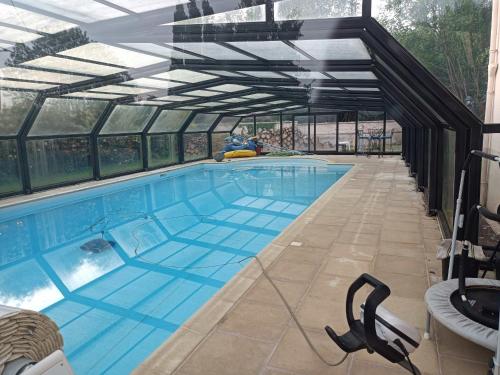 une grande piscine avec une enceinte en verre dans l'établissement Gîte rénové avec piscine dans le Gâtinais - FR-1-590-564, à Chantecoq