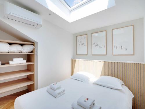 une chambre avec un lit blanc et une lucarne dans l'établissement Cosy & Modern Apartment - 1BR 4P - Montreuil, à Montreuil