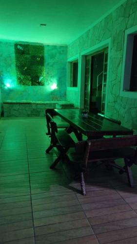 a ping pong table in a room with a green light at Hostel Canto da Alegria in Itanhaém