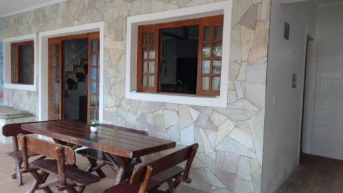 a dining room with a wooden table and a stone wall at Hostel Canto da Alegria in Itanhaém