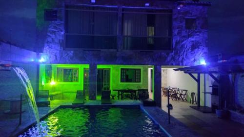 a house with a pool at night with green lights at Hostel Canto da Alegria in Itanhaém