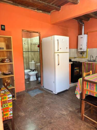 a white refrigerator in a kitchen with an orange wall at Suyay Wasi in Purmamarca