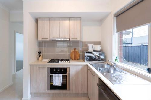 a kitchen with a stove top oven next to a sink at Modern 3B2B1C Home in Doreen in Doreen