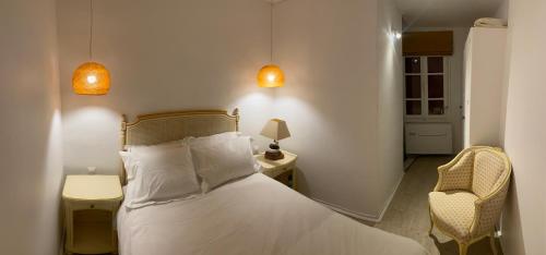 une chambre avec un lit blanc et une chaise dans l'établissement Charmante Maison de Village, à Banyuls-sur-Mer