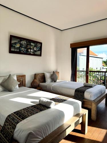 a bedroom with two beds and a balcony at Putu Homestay in Canggu
