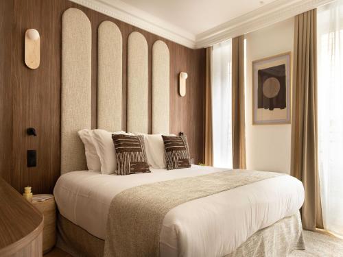 une chambre avec un grand lit avec des draps et des oreillers blancs dans l'établissement Elegant appt- AC-2BR-6P- Musée du Louvre, à Paris