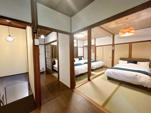a bedroom with two beds and a large mirror at 民宿ひだまり Minsyuku Hidamari in Kurashiki