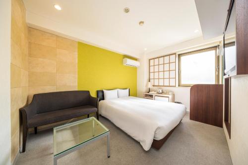a bedroom with a bed and a couch and a table at Hotel Cerezo in Tokyo