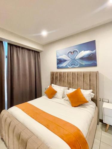 a bedroom with a large bed with orange pillows at Skynest Residences Nairobi, Westlands in Nairobi