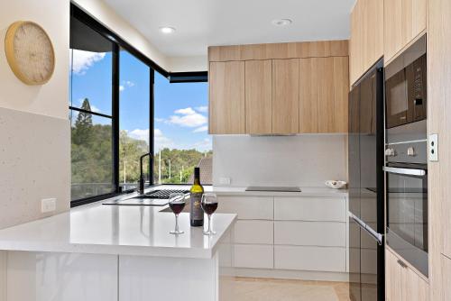a kitchen with two glasses of wine on a counter at Sea Breeze At Mudjimba Beachside, Tennis Pool in Mudjimba