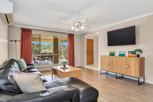 a living room with a couch and a flat screen tv at Vinea Vista - Hillside Homestead amid Rural Beauty in Lenswood