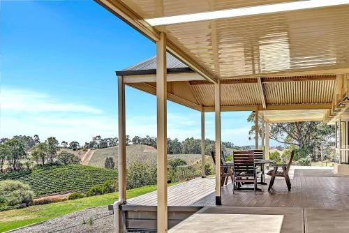 a wooden porch with a table and chairs on it at Vinea Vista - Hillside Homestead amid Rural Beauty in Lenswood