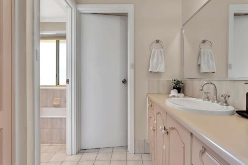 a white bathroom with a sink and a mirror at Vinea Vista - Hillside Homestead amid Rural Beauty in Lenswood