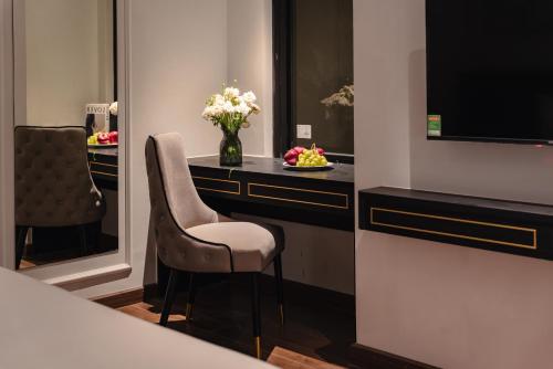 a room with a desk with a chair and a vase of flowers at 22Land Cloud Hotel in Hanoi