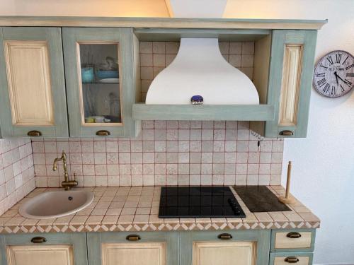 une cuisine avec un évier et une horloge murale dans l'établissement Appartement Vue sur la mer à 5 minutes des plages, à Villeneuve-Loubet