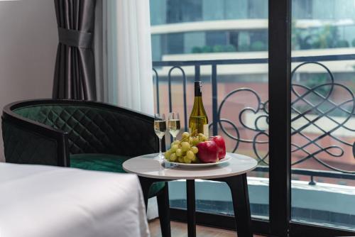 a table with a bottle of wine and a bowl of fruit at 22Land Cloud Hotel in Hanoi