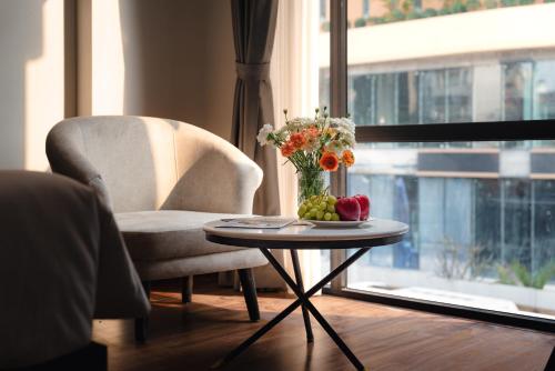a table with a vase of flowers and a chair at 22Land Cloud Hotel in Hanoi