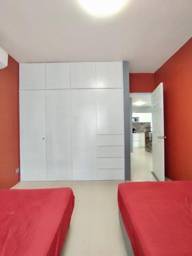 two beds in a room with red walls and white cabinets at Estancia rivera Cancún in Cancún