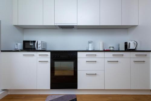 a kitchen with white cabinets and a black oven at KAYA Zurich Apartment 3B - Downtown 2BR Deluxe Apt in Zürich