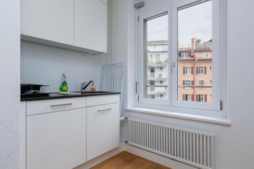 a kitchen with white cabinets and a large window at KAYA Zurich Apartment 3B - Downtown 2BR Deluxe Apt in Zürich
