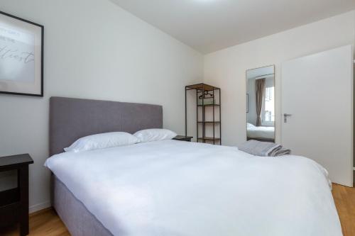 a bedroom with a large white bed and a mirror at KAYA Zurich Apartment 3B - Downtown 2BR Deluxe Apt in Zürich