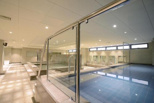 a swimming pool in a building with a glass wall at Astar Hotel in Jeju