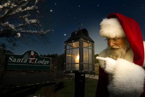 a man in a santa claus hat holding a lantern at Santa's Lodge in Santa Claus