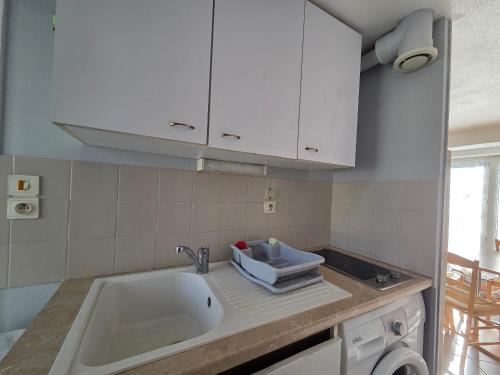 - une cuisine avec un évier et des placards blancs dans l'établissement Confortable duplex avec terrasse, proche plage et commerces - St Brevin l'Océan - FR-1-364-43, à Saint-Brévin-les-Pins