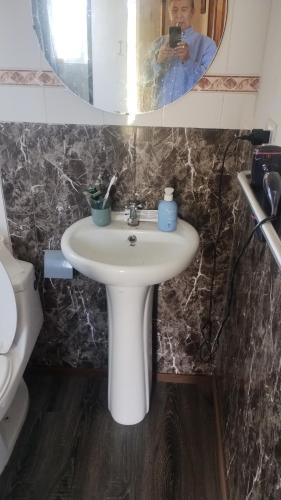 a bathroom with a sink and a person taking a picture in a mirror at Cabaña en condominio privada in Llanquihue