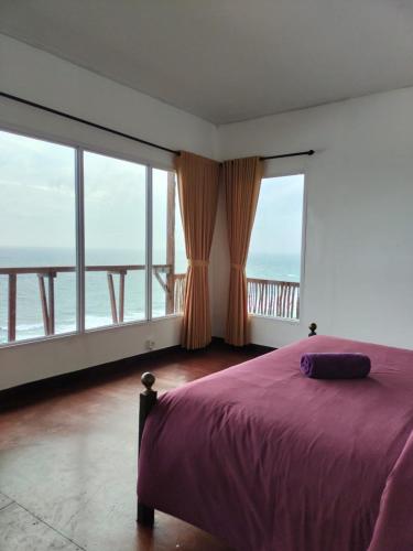 1 dormitorio con cama morada y ventanas grandes en Three Octopus by Walidwipa Paradise Hospitality, en Uluwatu