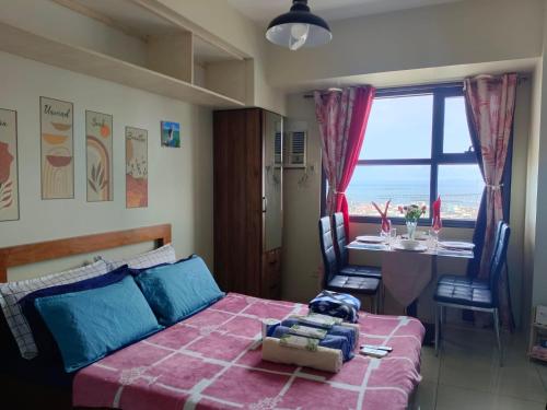 a bedroom with a bed and a table and a window at MaehwensStaycation in Cebu City