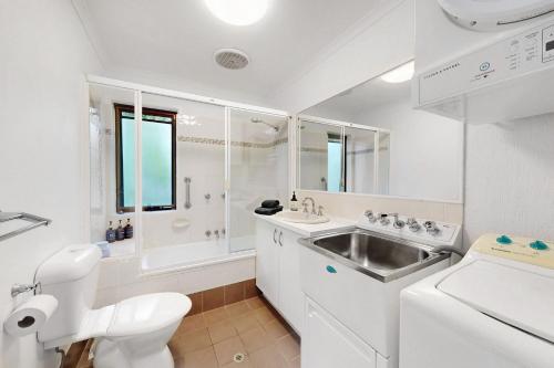 a white bathroom with a sink and a toilet at 4 Kurrambah at Noosa Sound in Noosaville