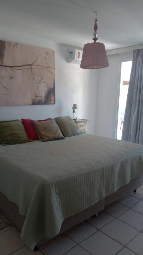 a bedroom with a large bed with a large window at Apartamento Solar das Artes in Morro de São Paulo