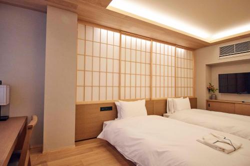 a hotel room with two beds and a television at MKG HOTEL Asakusa in Tokyo