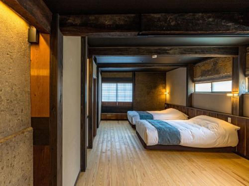 a row of three beds in a room at NIPPONIA Sado 佐渡相川 金山町 in Sado