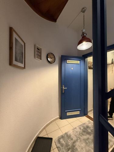 a blue door in a hallway with a clock on the wall at Nordseeglueck-im-Zentrum-Husums in Husum