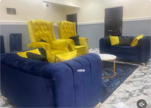 a living room with blue and yellow chairs and a table at Oxford Villa in Nnewi