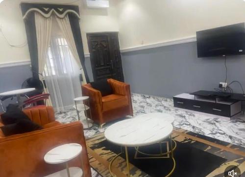 a living room with a table and chairs and a tv at Oxford Villa in Nnewi