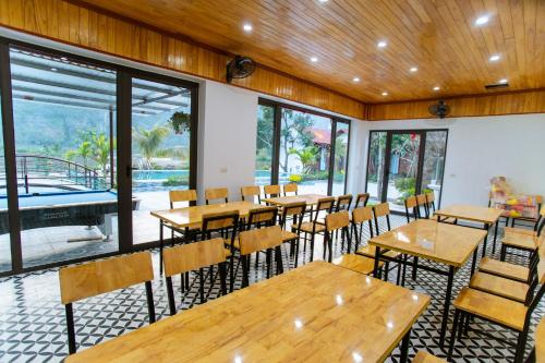 a restaurant with wooden tables and chairs and windows at Tam Coc Minh Quan Homestay in Ninh Binh