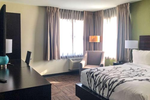 a hotel room with a bed and a desk and window at Sleep Inn & Suites Quebec City East in Boischâtel