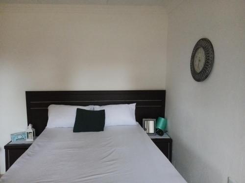 a bedroom with a bed with a clock on the wall at Mama Olly & Sons Guest House in Vosburg